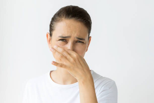 Bad Smell Caucasian female holding nose and is looking at camera. Representing bad smell and disgust. unpleasant smell stock pictures, royalty-free photos & images