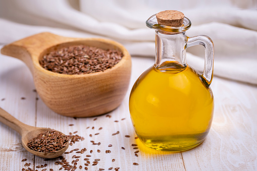 Flaxseed oil is rich in vitamin A, E, D, F and omega-3, omega-6 and omega-9. Linseed oil in a glass vessel and close-up flax seeds. The concept of healthy eating.