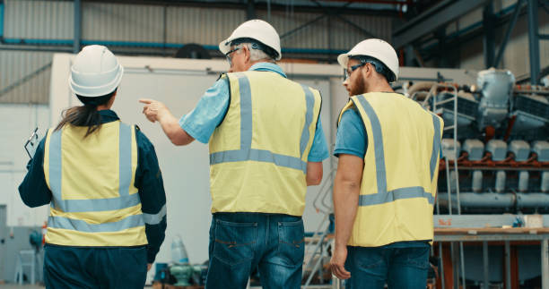 fertigungs-, bau- und facharbeiter bauen, planen und arbeiten an designarbeiten in einem distributionslager. logistiker, techniker und architekten gehen zusammen - safety meeting construction site construction stock-fotos und bilder