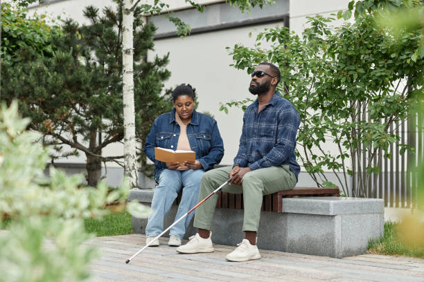 istock Woman Reading Book to Blind Partner in Park 1415350008