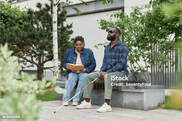 Woman Reading Book to Blind Partner in Park
