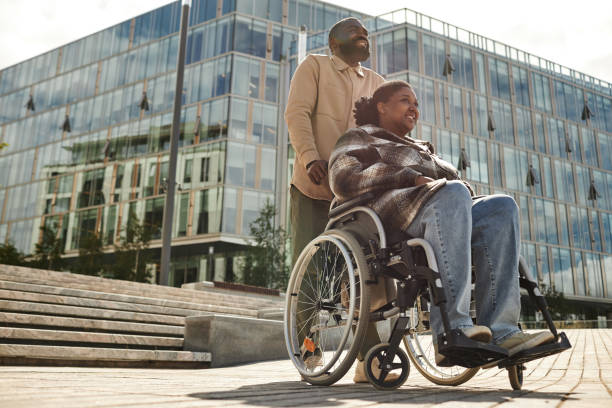 istock Couple with Partner in Wheelchair City Setting 1415350128