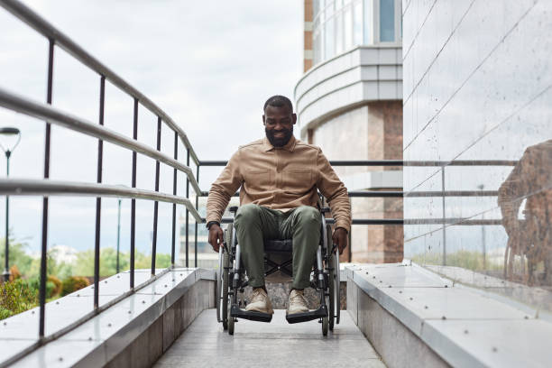 Smiling Man with Disability using Ramp Full length portrait of smiling man with disability going down ramp in city, urban accessibility, copy space african american architecture stock pictures, royalty-free photos & images