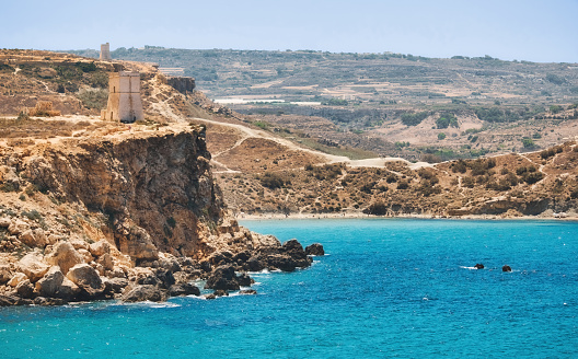 A view of the cliff and Ghajn Tuffieha Tower from Golden Bay in Mellieha, Malta