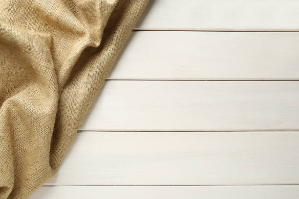 istock Natural burlap fabric on white wooden table, top view. Space for text 1415352707