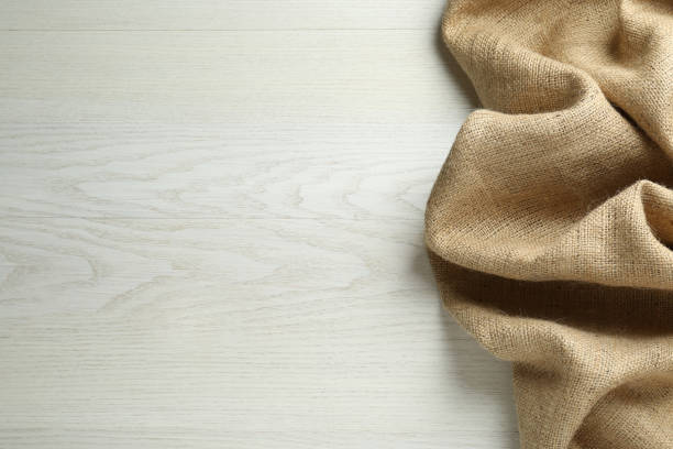 istock Natural burlap fabric on white wooden table, top view. Space for text 1415352722