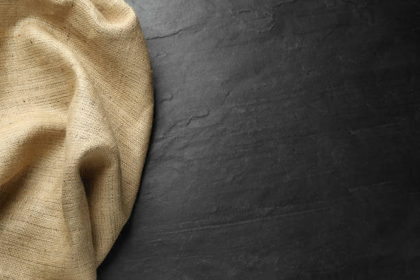 istock Natural burlap fabric on black table, top view. Space for text 1415352925