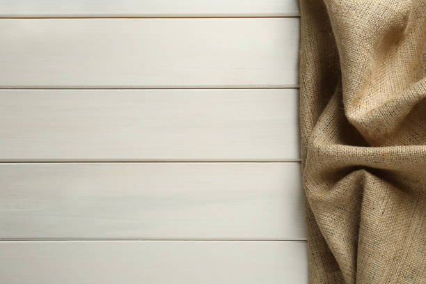 istock Natural burlap fabric on white wooden table, top view. Space for text 1415353153