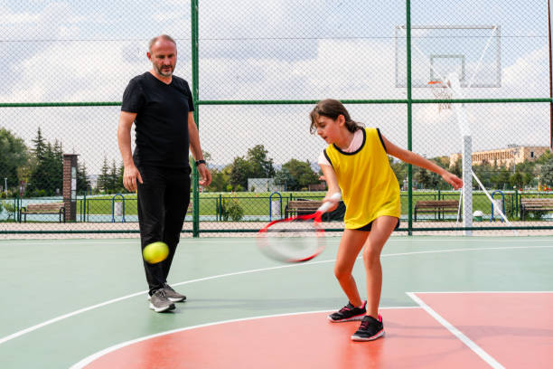 istock coach teaching his daughter to play tennis 1415354221