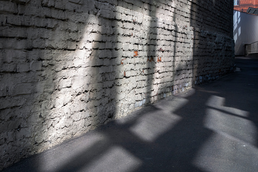 Passage along old brick wall on sunny day.