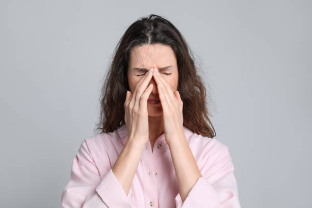 istock Mature woman suffering from headache on light grey background 1415354719