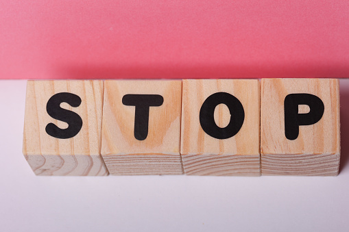 STOP  word on wooden cubes on pink background