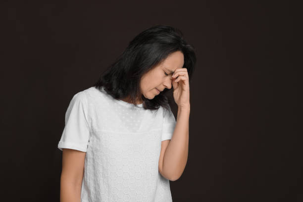 istock Mature woman suffering from headache on dark brown background 1415354802