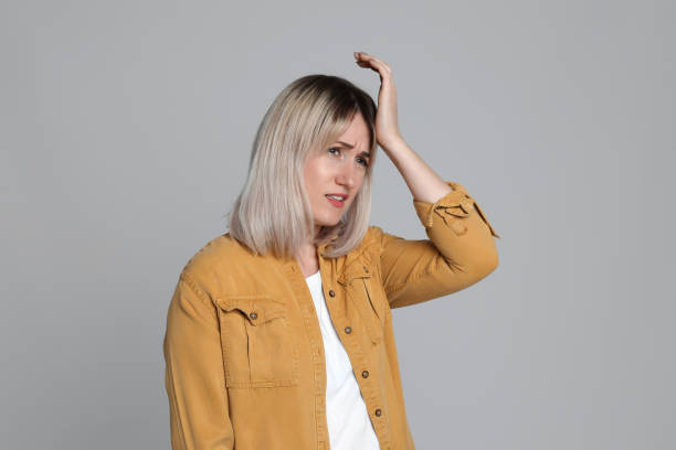 istock Woman suffering from headache on light grey background 1415354803
