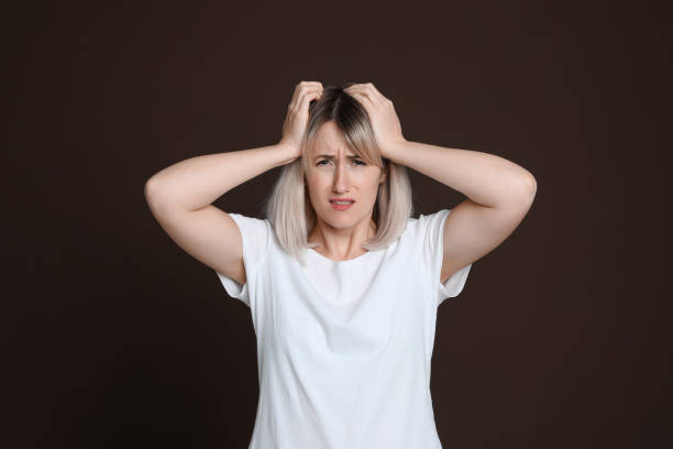 istock Woman suffering from headache on dark brown background 1415354877