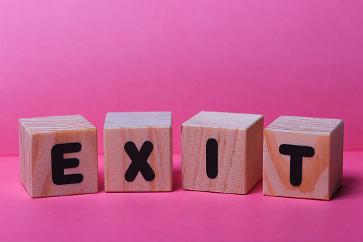 EXIT  word on wooden cubes on pink background