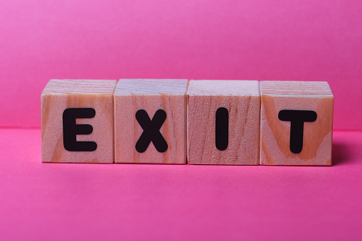 EXIT  word on wooden cubes on pink background