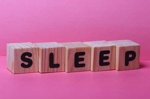 SLEEP  word on wooden cubes on pink background