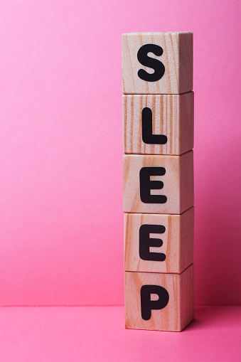 SLEEP  word on wooden cubes on pink background