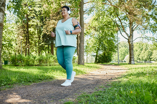 Mujer con sobrepeso corriendo en el parque photo