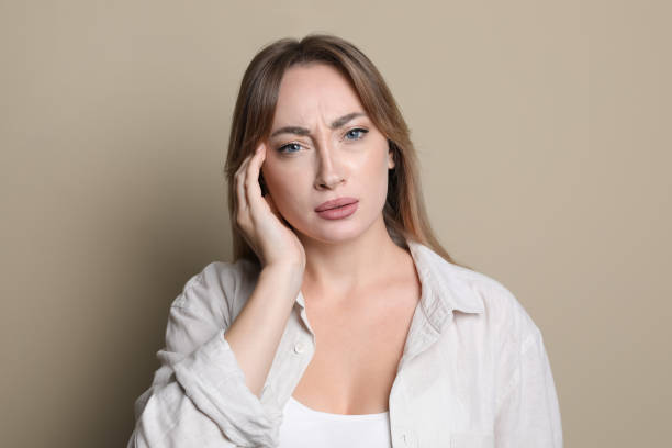 istock Young woman suffering from headache on beige background 1415356488
