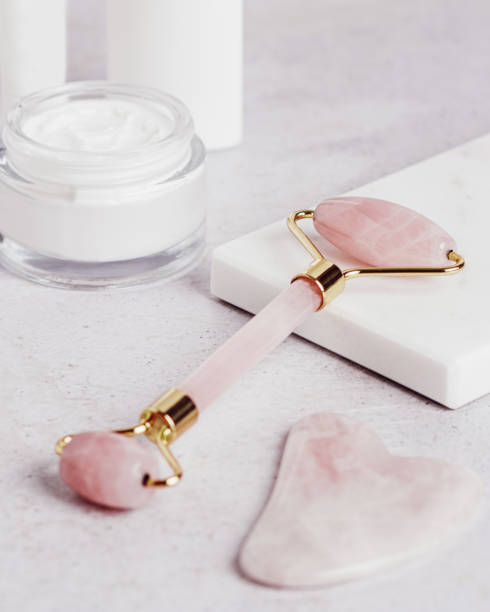 istock Facial roller, gua sha, serum and moisturizing cream on marble background 1415356583