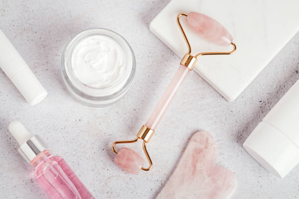 istock Facial roller, gua sha, serum and moisturizing cream on marble background 1415356592