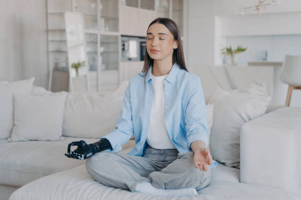 istock Tranquil disabled woman is sitting in lotus pose. Modern artificial limb with sensor control. 1415357479