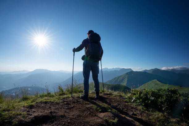 istock Hiker stands alone on top of the mountain at sunset, rear view 1415357708