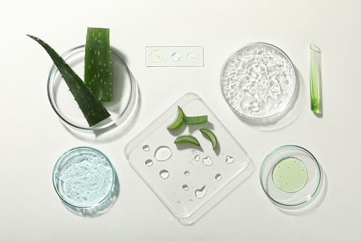 Flat lay composition with cosmetic gel, laboratory glassware and aloe on white background