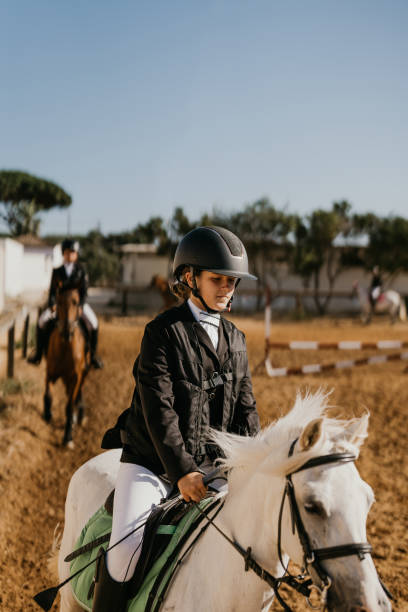 une fillette de 12 ans faisant du jogging avec un poney blanc à l’école d’équitation - running horses photos et images de collection