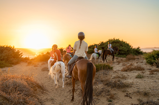 group of young riders on horseback heading towards the beach. Sea