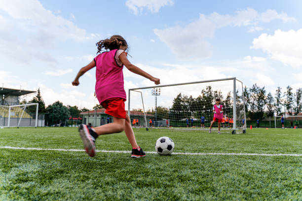 niños practicando tiros penales y jugando al fútbol. portera jugando al fútbol con una amiga - soccer ball youth soccer event soccer fotografías e imágenes de stock