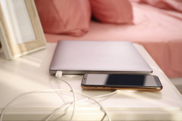 istock Smartphone with wireless charger connected to laptop on white table in bedroom 1415358981