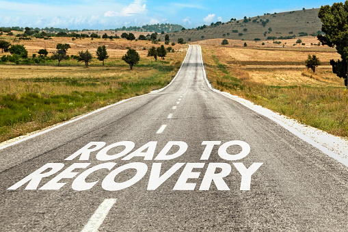 Road to recovery text on asphalt road