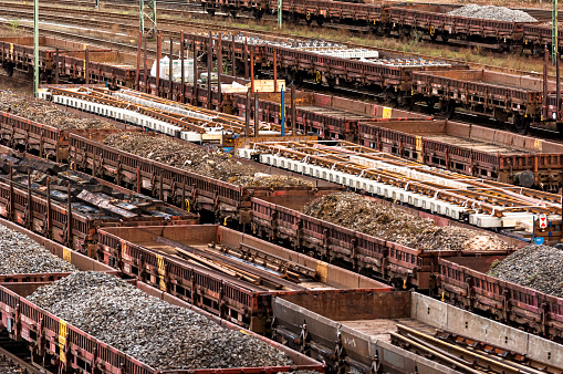 Open freight wagons, some with stanchions and loaded with coal, ballast, tracks and scrap metal, wait at a marshalling yard for onward transport