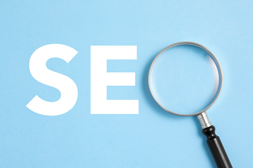 Magnifying glass compliting SEO word on blue background