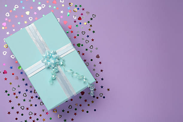 istock Light blue gift box and sequins on lilac background, flat lay. Space for text 1415359539