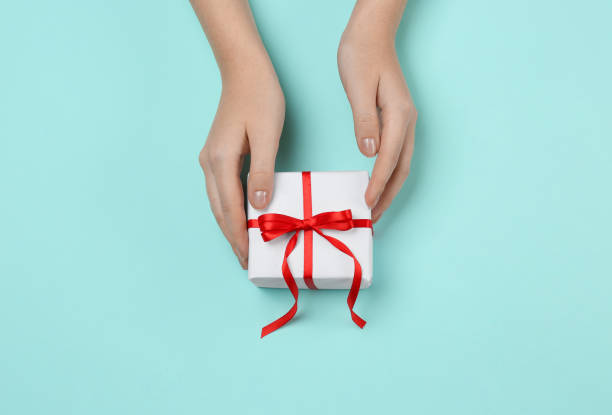 istock Woman holding beautiful gift box on turquoise background, top view 1415359696