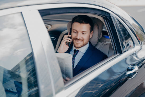 happy young business owner reading newspaper in car - limousine imagens e fotografias de stock