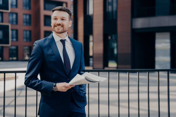 istock Happy office worker on break standing while holding newspaper 1415359858
