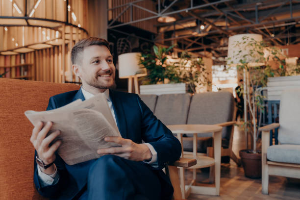 istock Positive young businessman reading newspaper in cafe 1415359882