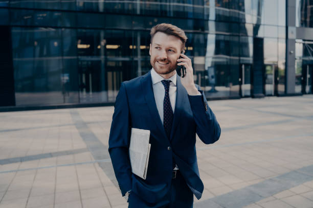 istock Happy office worker with newspaper talking on smartphone 1415359897