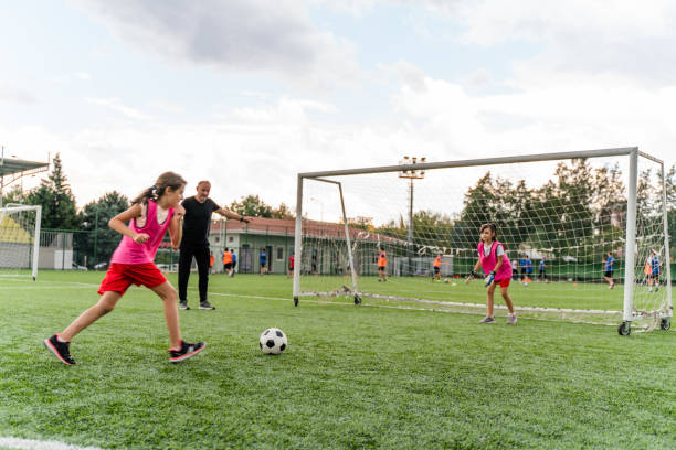 kids practicing penalty kicks and playing soccer. female goalkeeper playing football with friend - soccer ball youth soccer event soccer imagens e fotografias de stock