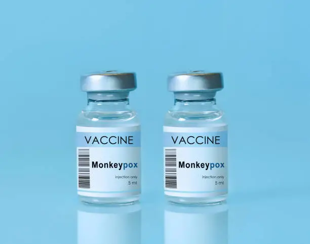 Photo of Two vials with vaccine Monkeypox on a blue background.The concept of medicine, healthcare. Monkeypox is a viral zoonotic disease. Monkeys may harbor the virus and infect people.