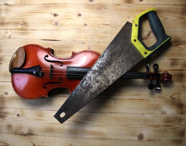 Violin and hacksaw on wooden background