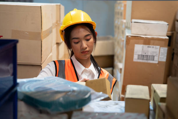 istock Worker in the warehouse factory standing arrange the boxes on shelf and using table key in information 1415363533