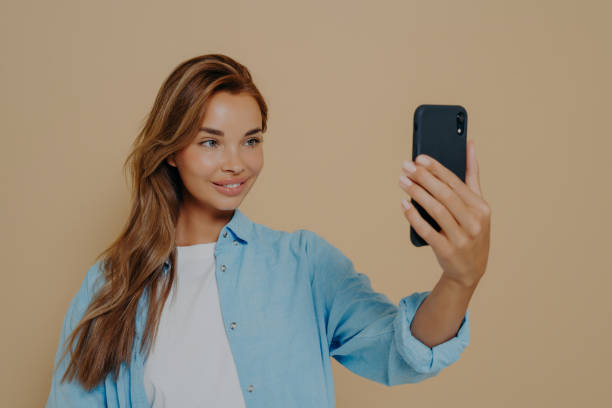 istock Adorable female model poses for making selfie in studio 1415364043