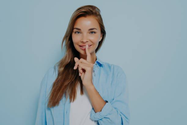istock Pretty female placing fingers on lips making sign symbol 1415364096