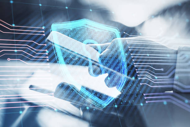 istock Close up of businessman hands using tablet and smartphone on desktop and creative glowing shield circuit security hologram on blurry background. Safety and web protection concept. Double exposure. 1415364556